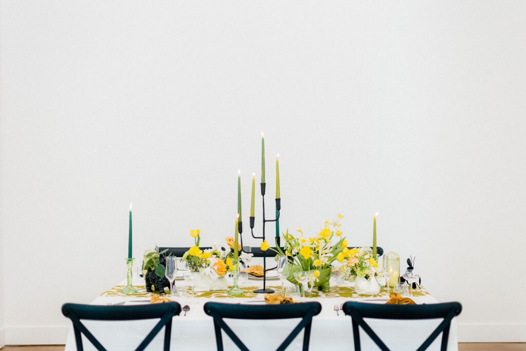 Green and yellow tablescape with candles and oddities designed by the floral eclectic.